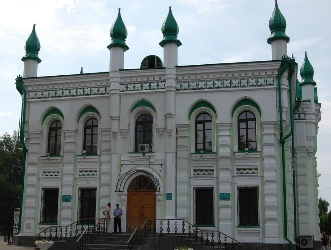 White and green historic building with onion domes, arched windows, and a wooden entrance door in Uralsk, a West Kazakhstan hub for reaching Saykhin.