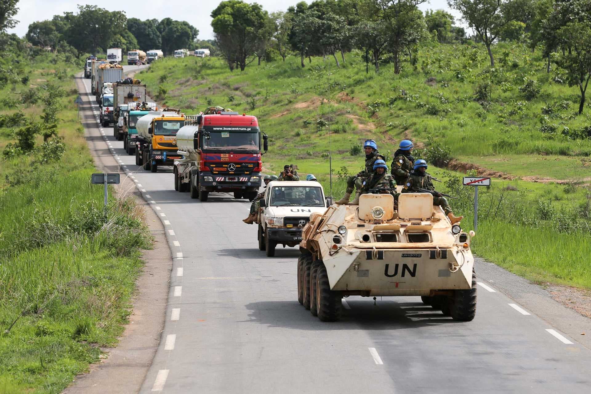 UN armored vehicle and convoy of trucks on a rural highway in the Central African Republic