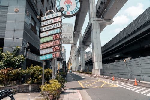 Urban street scene in Banqiao featuring a vertical distance signpost and elevated highway infrastructure under a bright sky.