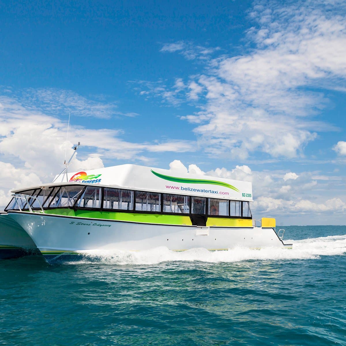 A white and green water taxi boat named 3 Stars Odyssey speeds across turquoise ocean waters under a blue sky with scattered clouds.