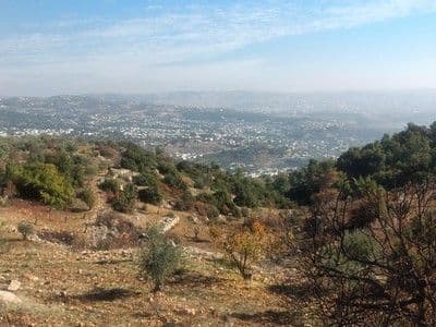 Hillside view overlooking a valley village in northern Jordan under a hazy blue sky