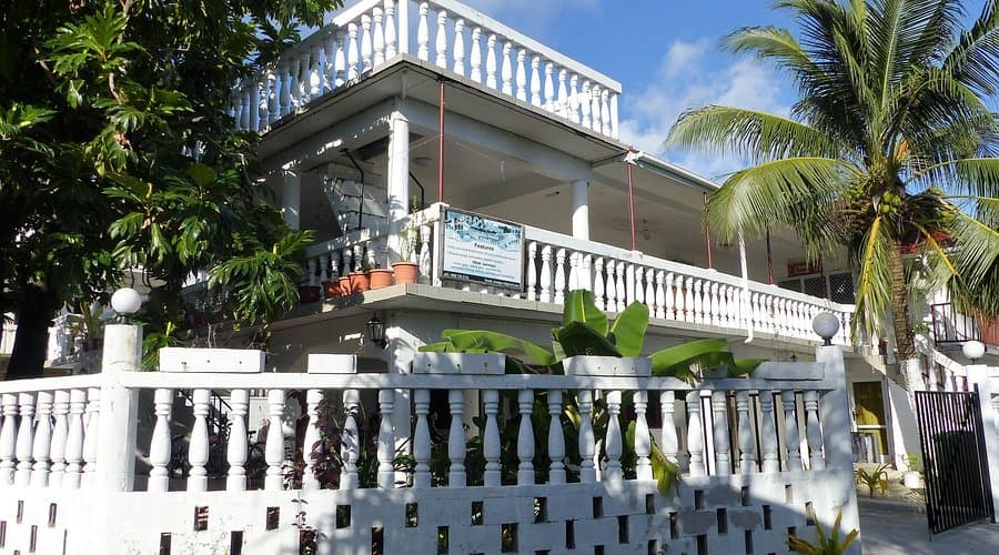 Exterior view of L's Lodge in Fakaifou, a white two-story guesthouse with balconies surrounded by tropical vegetation.