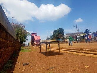Wide view of a dusty town street in the Afar Region with low tables, simple buildings, and a clear blue sky.