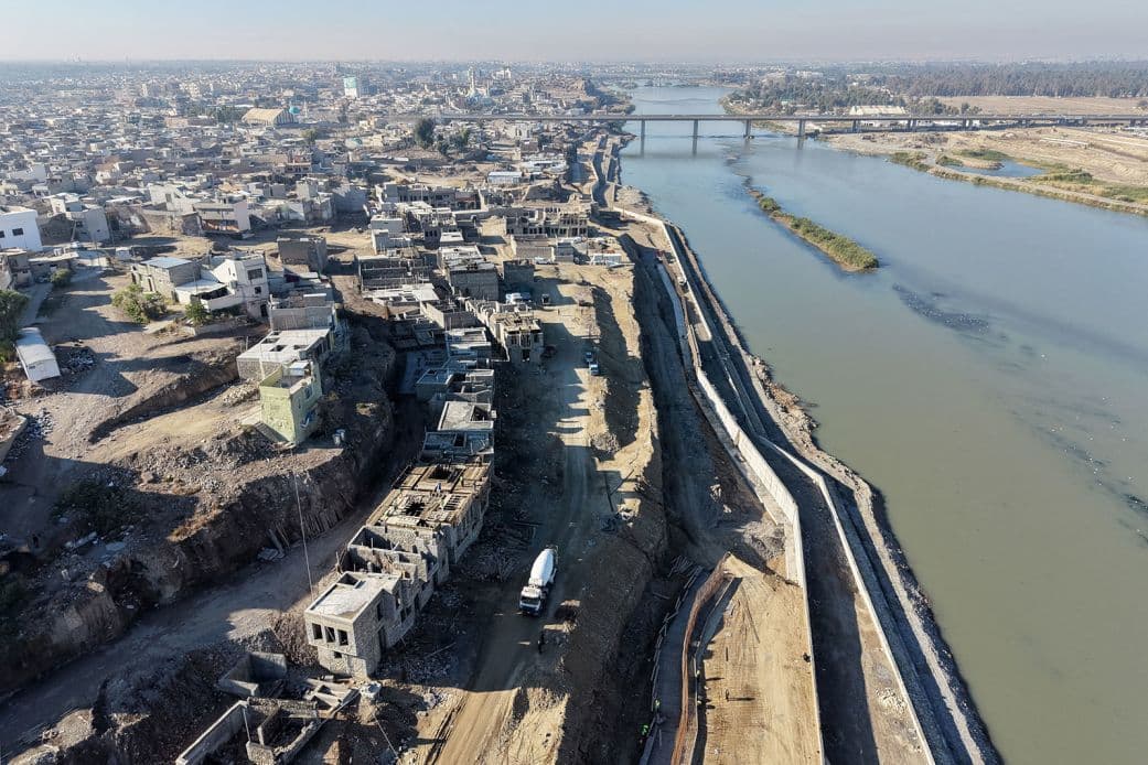 Aerial view of the Tigris River flowing through Mosul, with a bridge in the distance and urban development along the banks.