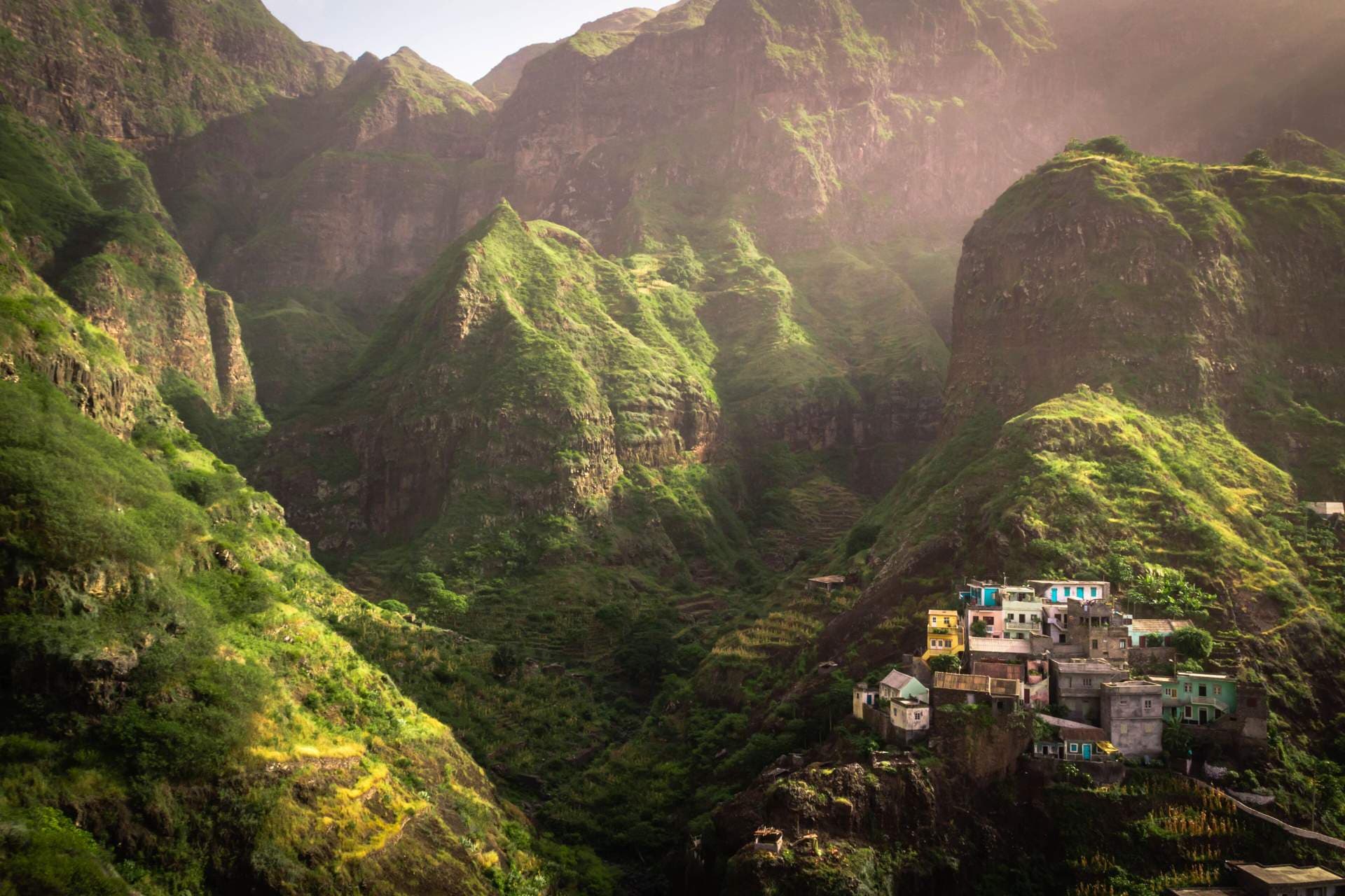 Vibrant green mountainous landscape featuring a small village nestled on steep slopes, characteristic of Santo Antão, Cape Verde.