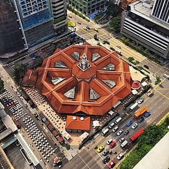Exterior of Lau Pa Sat, a historic food market in Singapore, with its distinctive architecture and surrounding cityscape