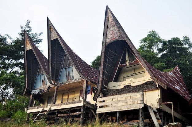 Exterior view of traditional Batak wooden houses with distinctive sharp, boat-shaped roofs in Ambarita village, surrounded by lush greenery.