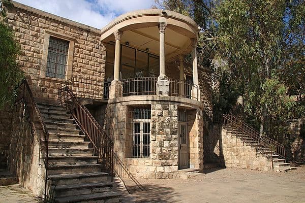 A stone building with a curved balcony and stairs in a village setting in Jordan