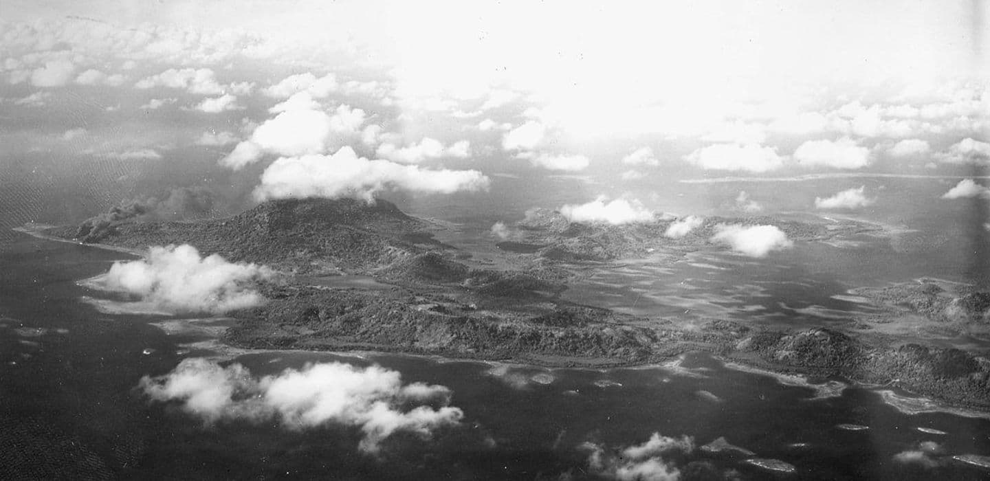 Aerial photograph of an island landscape with a lagoon, shoreline, and scattered clouds