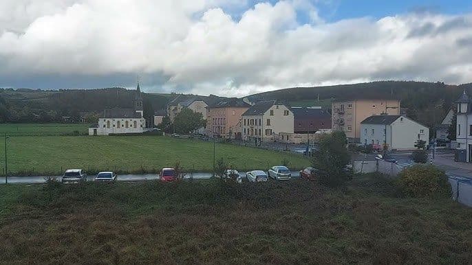 Scenic view of Warken village featuring a white church and residential buildings amidst rolling green hills.