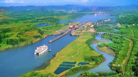 Aerial view of a river valley with green fields, bridges, and a cruise ship near Mirono, Panama.