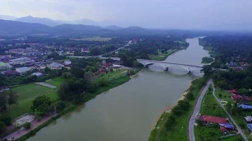 Aerial view of the Perak River flowing through Kuala Kangsar town, with a bridge and surrounding greenery