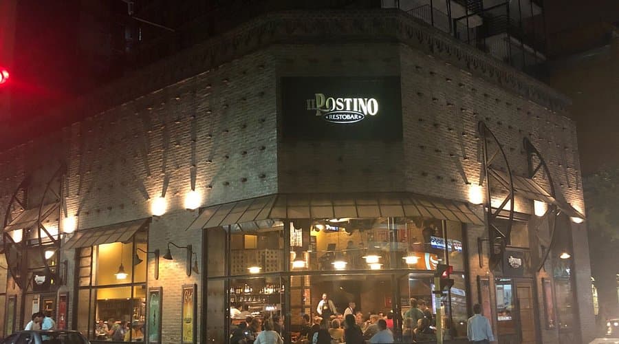 Restaurant entrance and street scene at dusk in San Miguel de Tucumán with warm lighting