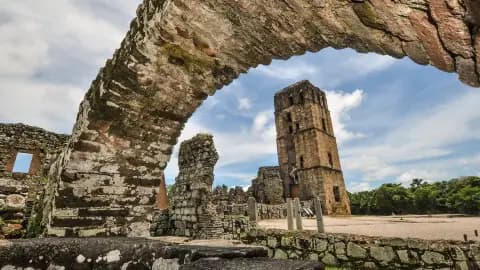 Stone archway framing a ruined tower and walls under a cloudy sky in Mirono, Panama.
