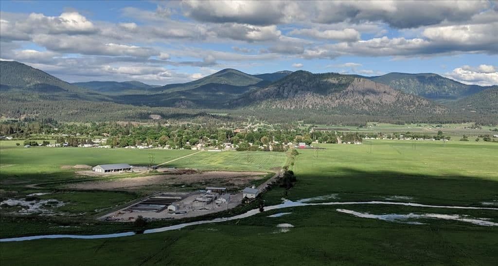 Aerial view of Chewelah, Washington, a small town in a green valley with mountains and pine forest in the background.