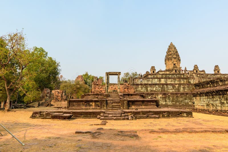 Exterior view of Prasat Bakong temple mountain under a clear sky, showcasing its stepped stone platforms and ancient Khmer architecture.