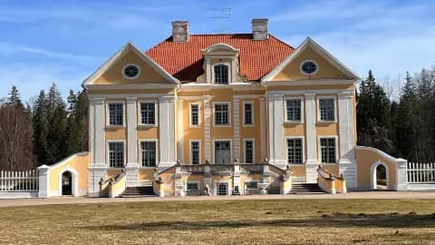 Yellow and white historic manor building with red roof and columns in Kadrina Parish, Estonia