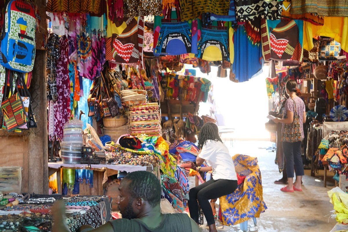 Market stall with colorful goods and textiles in a busy outdoor market in Sierra Leone.