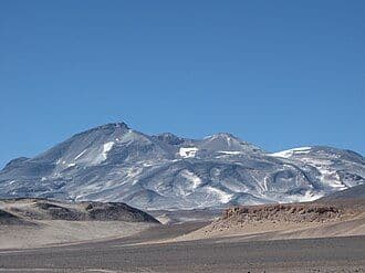 Desert mountain landscape with snow-capped peaks under a clear blue sky in the Copiapó region