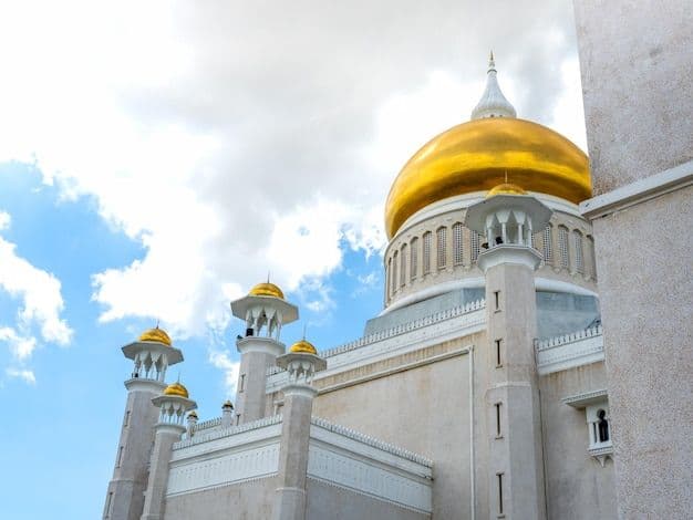 Exterior view of the Sultan Omar Ali Saifuddien Mosque in Bandar Seri Begawan, featuring its prominent golden dome and minarets against a cloudy blue sky.