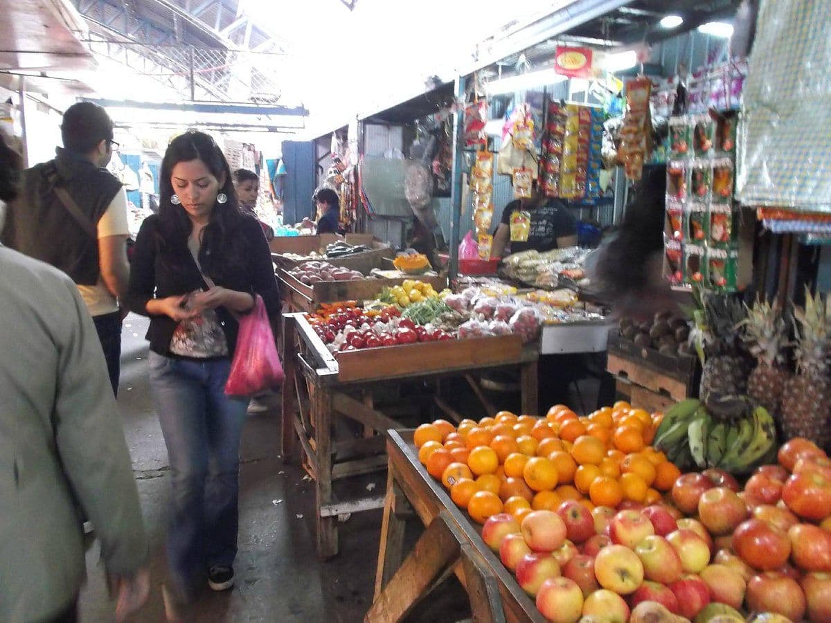 Covered market with wooden stalls displaying piles of fresh fruit and produce at Skeldon market