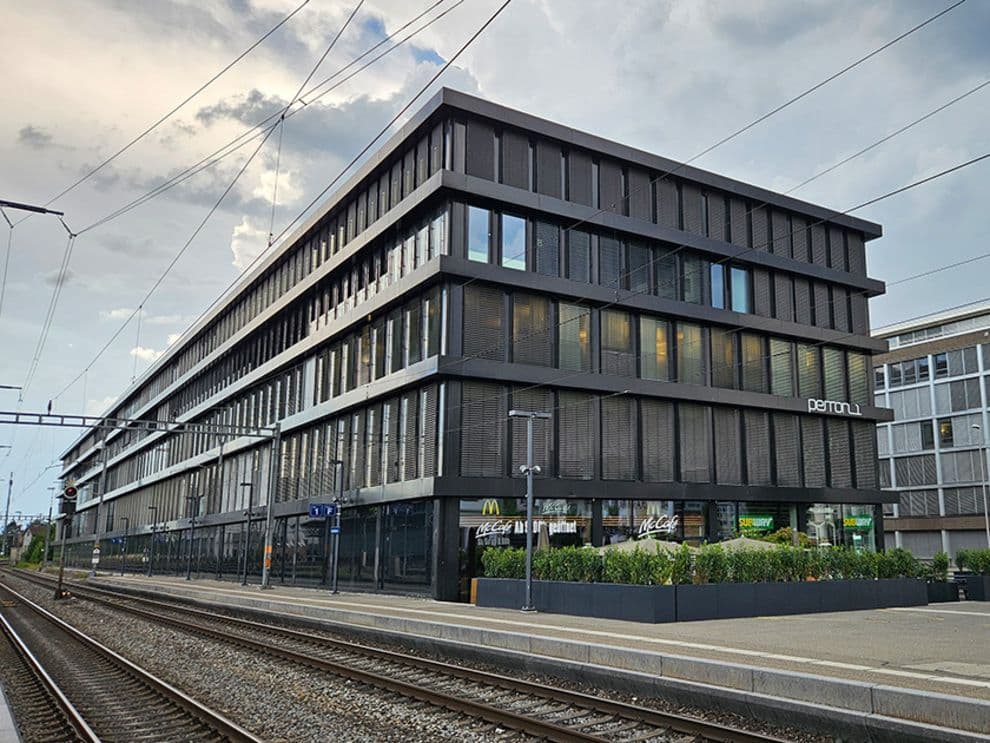 Modern building with dark facade and glass windows beside railway tracks at Solothurn station.