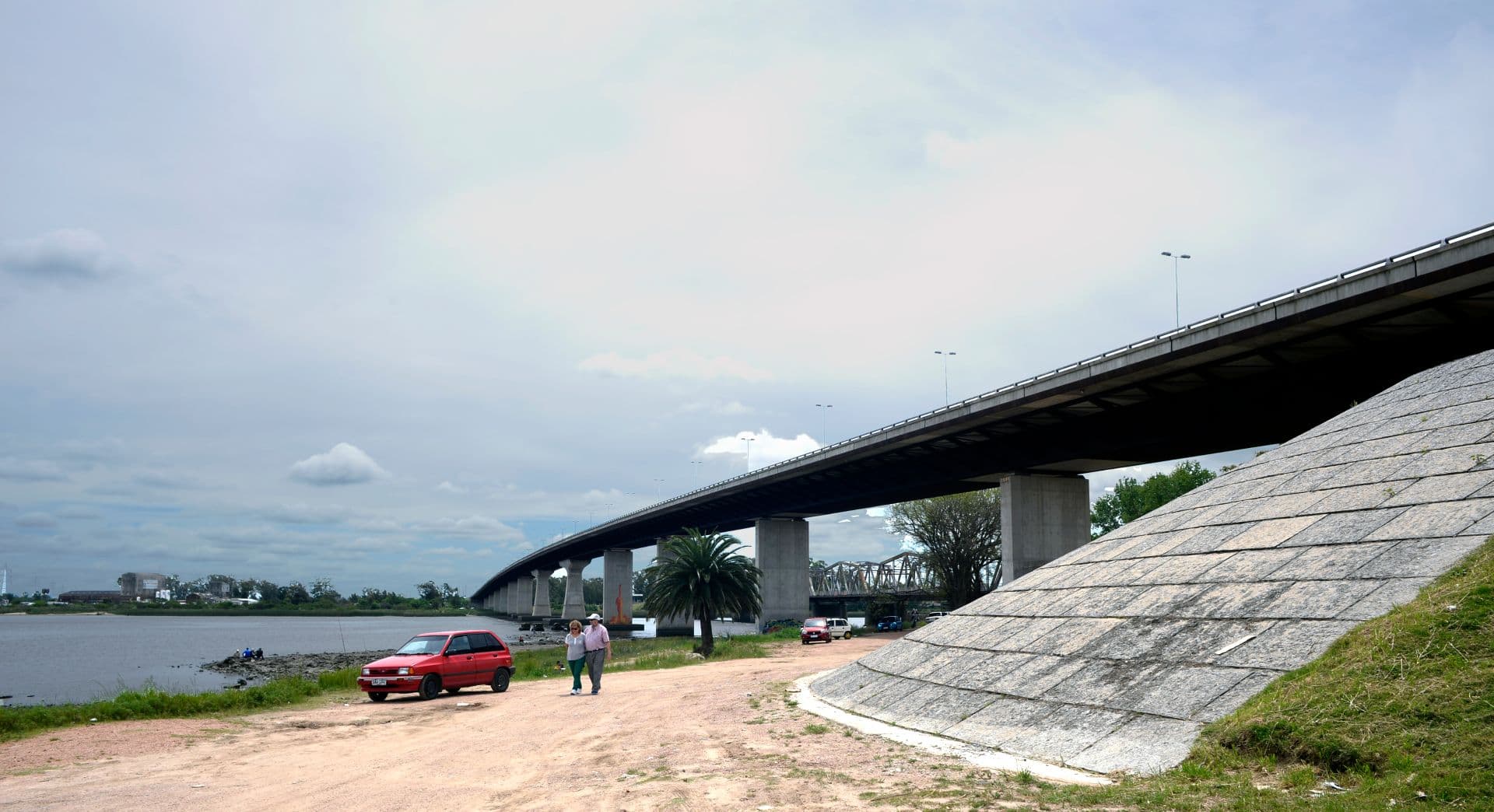Wide-angle view of the modern Ruta 1 bridge over the Santa Lucía River at Santiago Vázquez with the historic truss bridge behind it