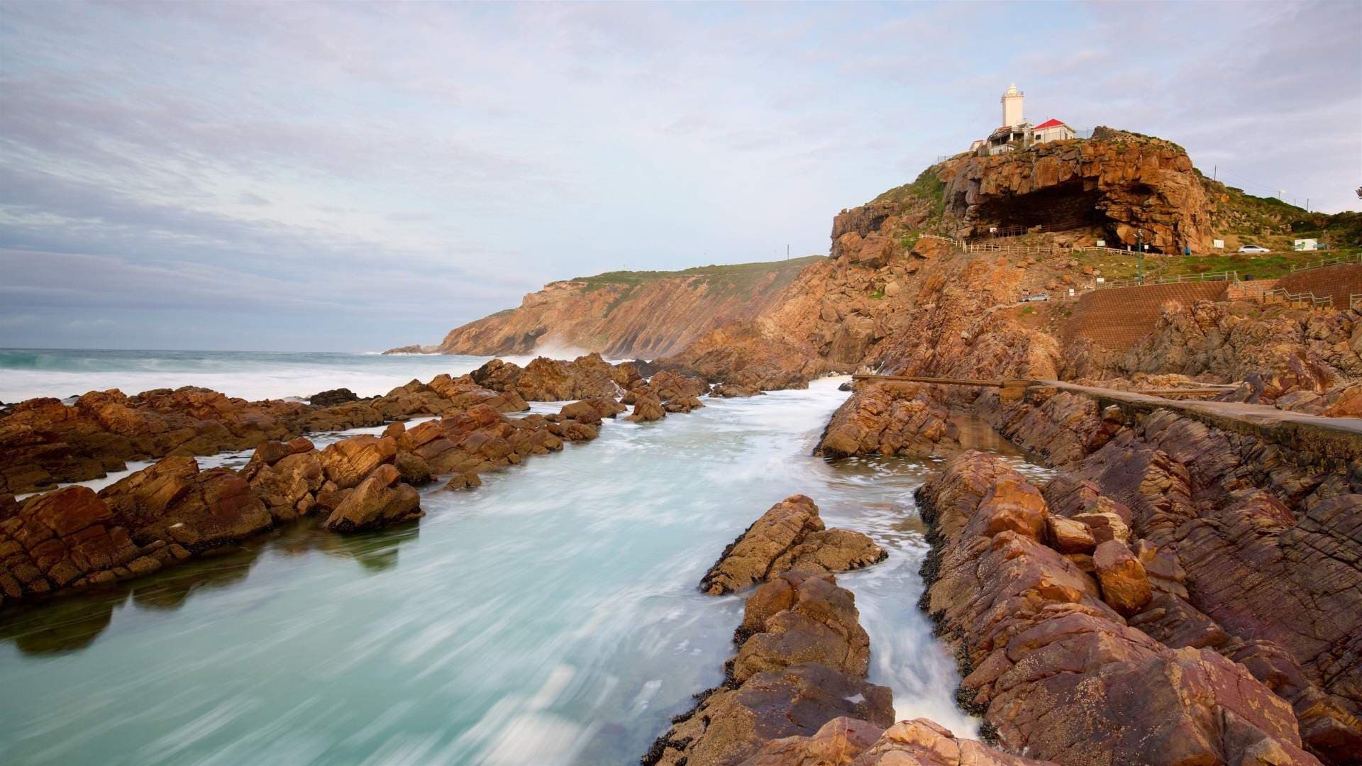Coastal cliffs, lighthouse, and rocky shoreline with surf at The Point, Mossel Bay.