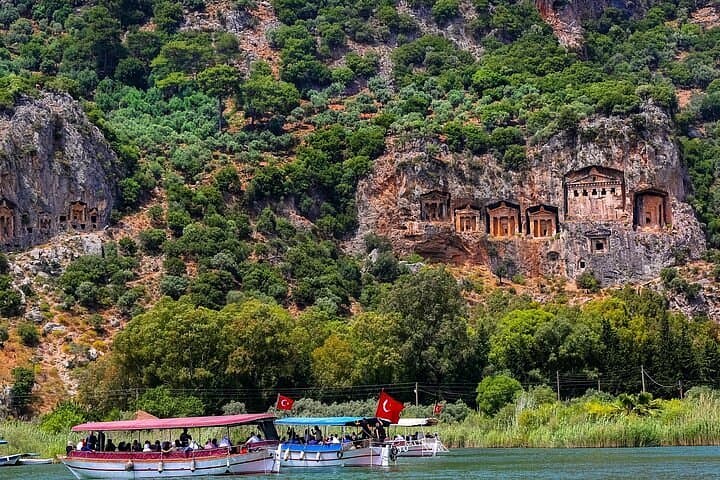 Tour boats on the Dalyan River pass beneath the ancient Lycian Rock Tombs carved into the cliffside.