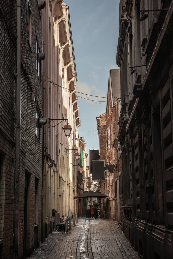 Narrow pedestrian alley with historic building facades and cobblestones in Amay, Belgium