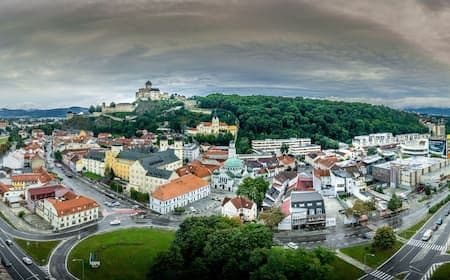 Aerial view of Bánovce nad Bebravou with the hilltop castle, town buildings, and the Bebrava River valley under a cloudy winter sky.