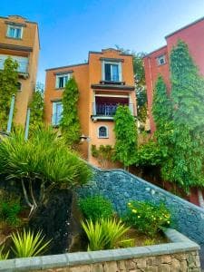 Colorful terraced houses with balconies and lush greenery on a hillside, depicting a residential landscape in Terre Rouge, Mauritius.