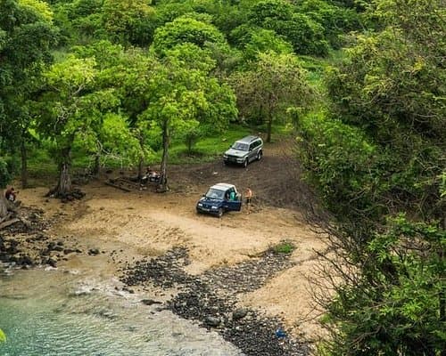 A 4x4 vehicle on a dirt road in the countryside of Trindade, Sao Tome and Principe, surrounded by lush vegetation