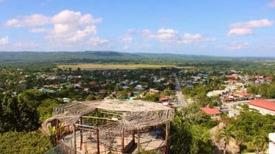 Elevated view of a rural village with scattered houses and green fields under a blue sky.