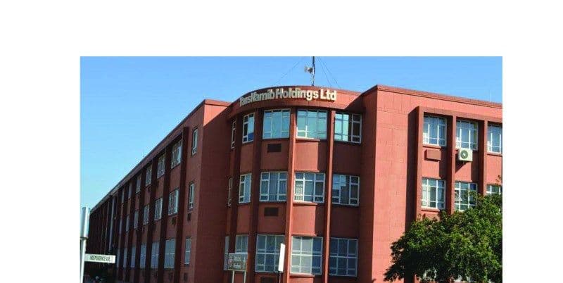 Red multi-story TransNamib Holdings Ltd building exterior under a clear blue sky.