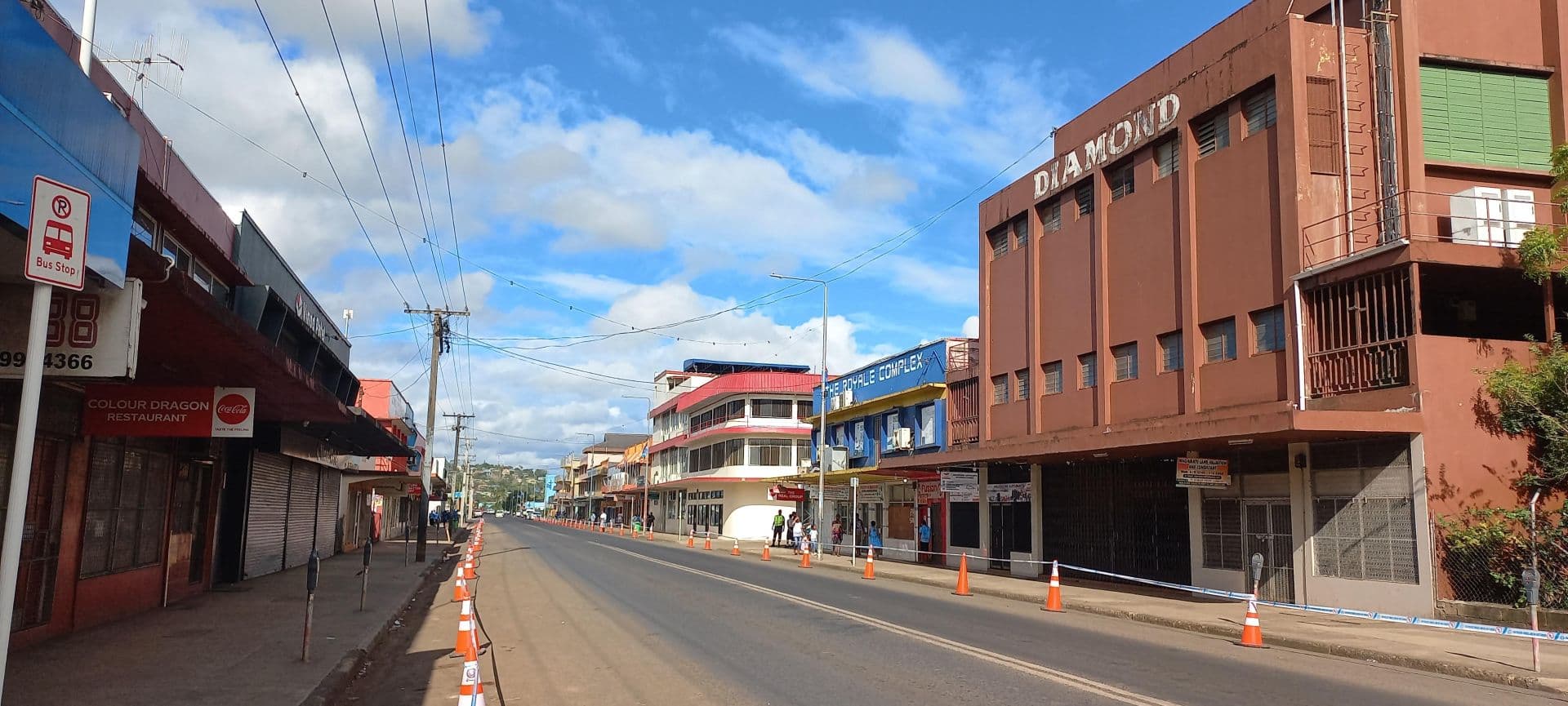 Wide street view of Labasa main street featuring the Diamond building and other commercial structures under a blue sky with scattered clouds.