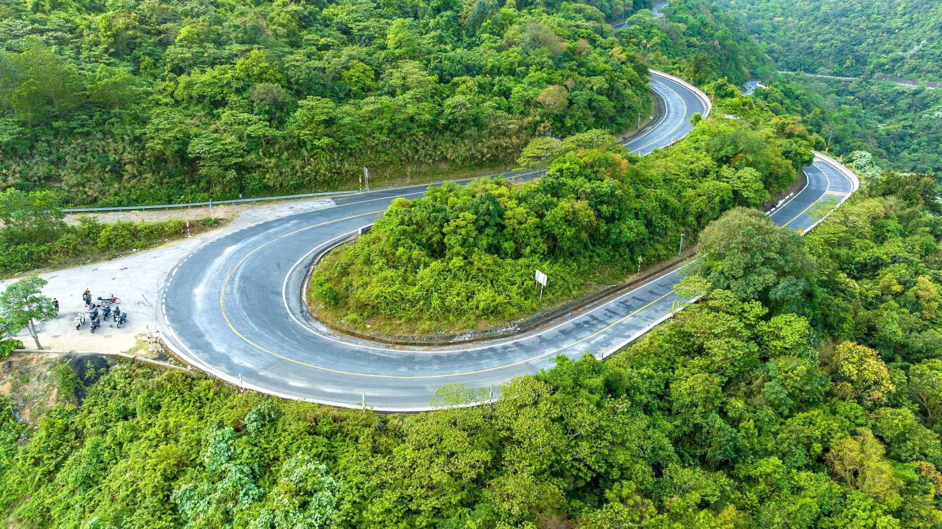 Aerial view of a winding paved mountain road with hairpin turns cutting through dense green highland vegetation on the route to La Mitra, Chiriquí, Panama.