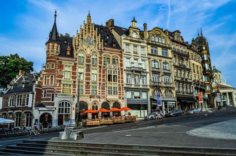 A street-level view of historic buildings in Bernissart featuring a prominent red-brick structure with a spire and outdoor cafe seating.