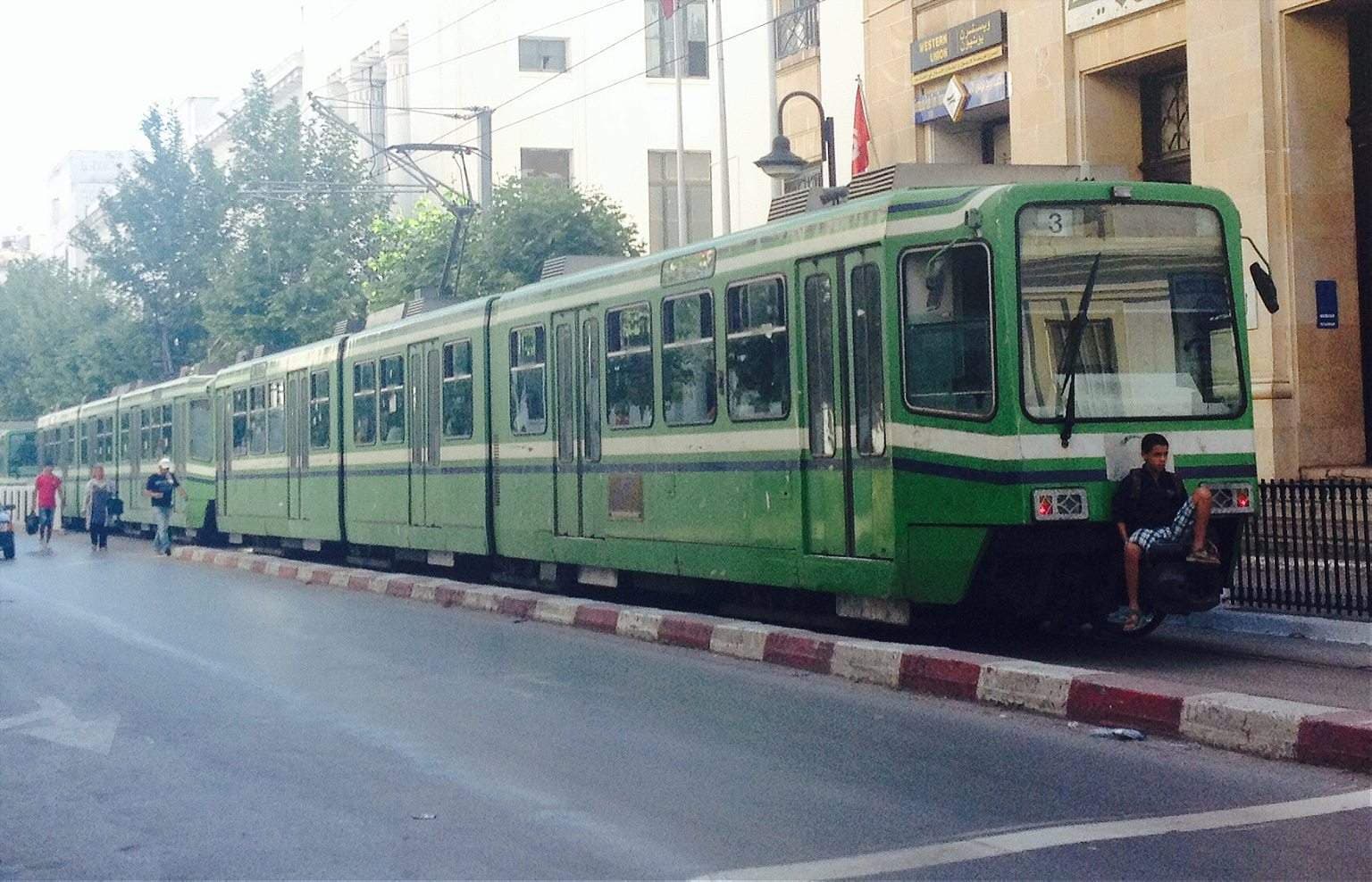 Green Tunis light metro train stopped at a street-level station, the modern transit link serving Ben Arous.