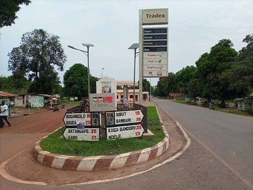 A paved road stretches into the distance past a central traffic island with directional signs and a tall signpost