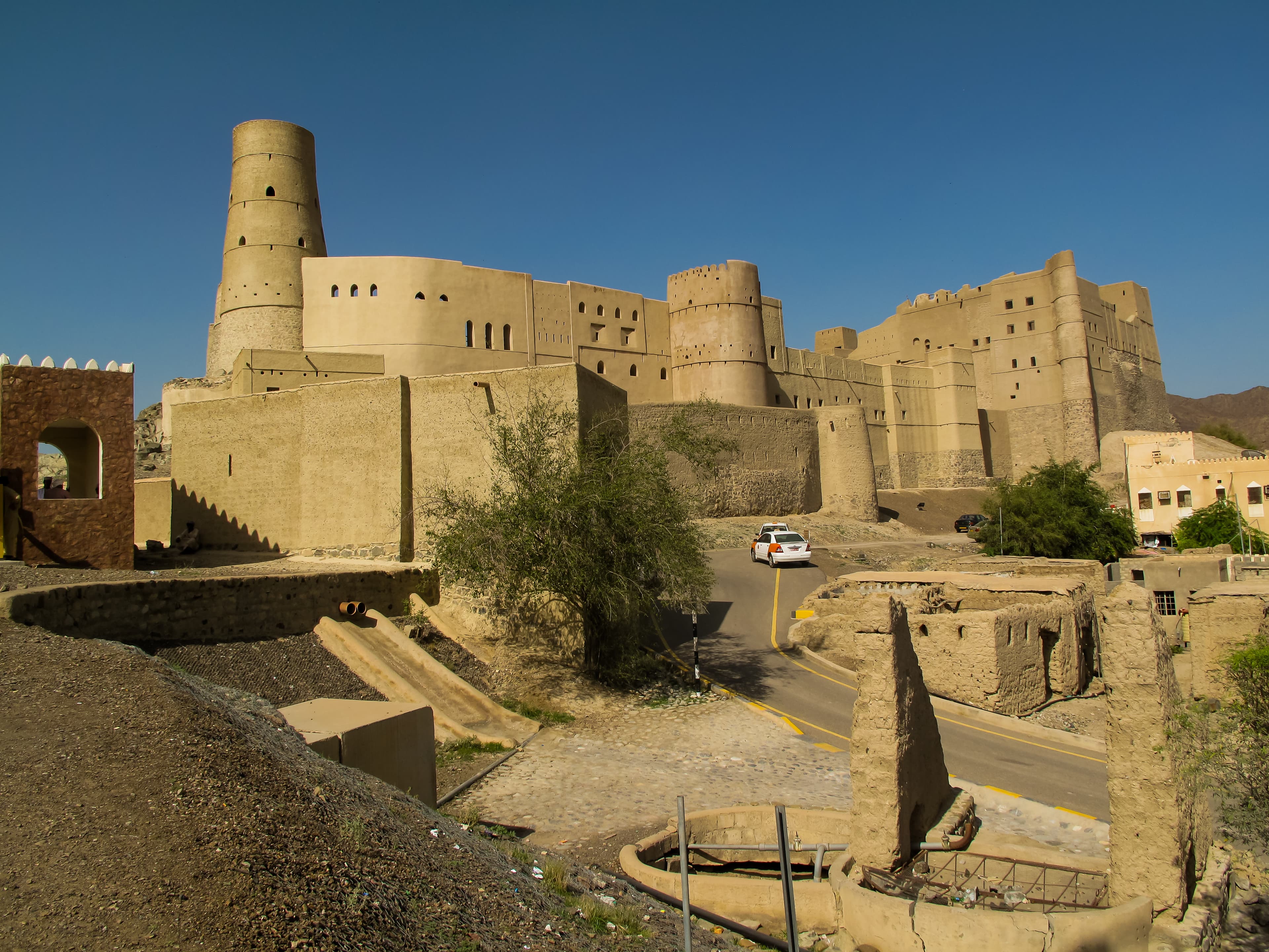 Exterior of Bahla Fort in Bahlā’, Oman, showcasing its massive mud-brick walls and historic towers