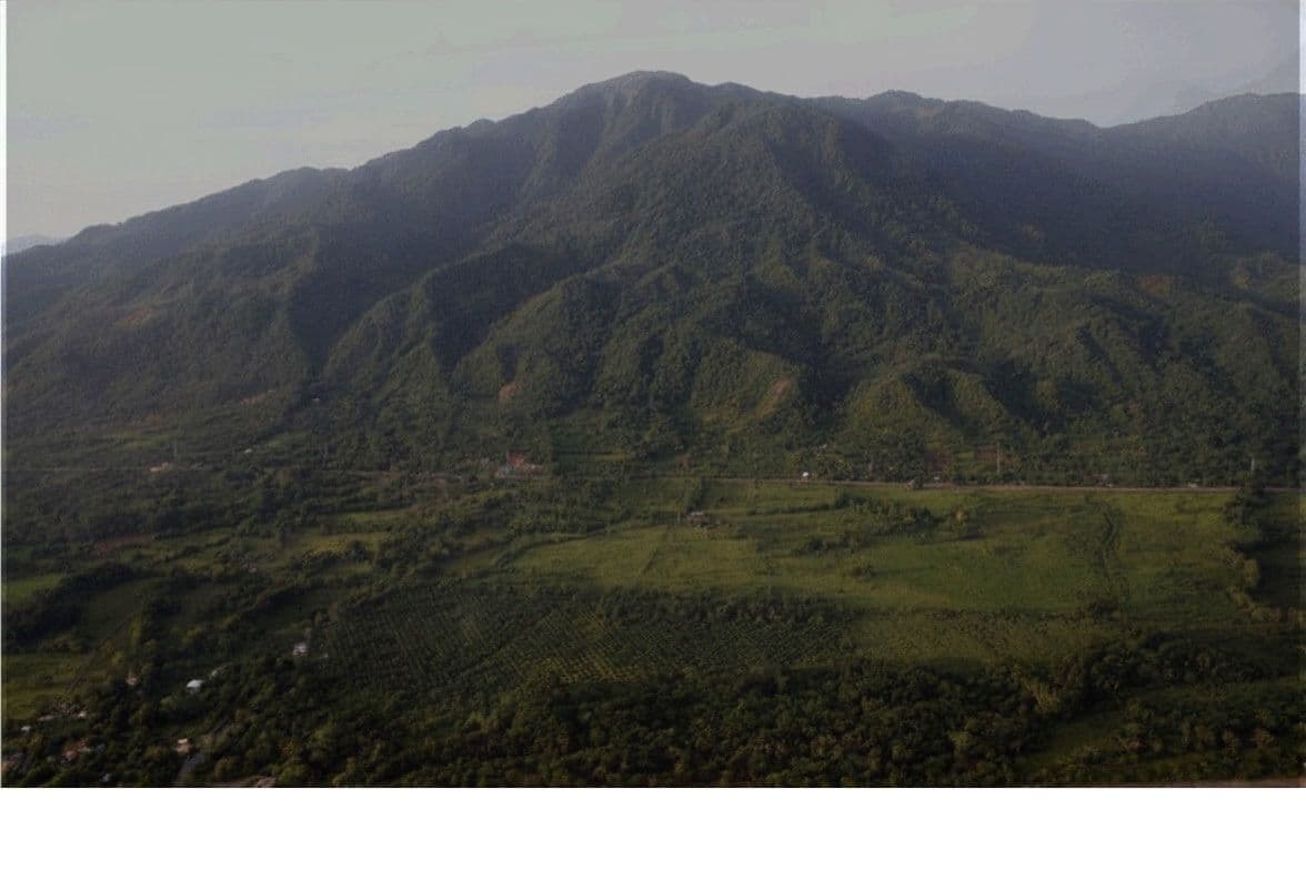 Aerial view of lush green tropical hills and valley with terraced fields.