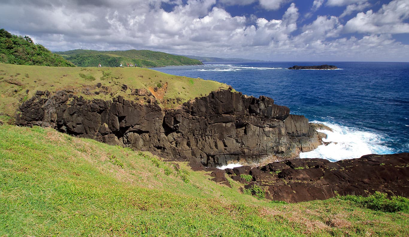 Wide view of the rocky coastline and clear blue ocean at Binurong Point in the Philippines