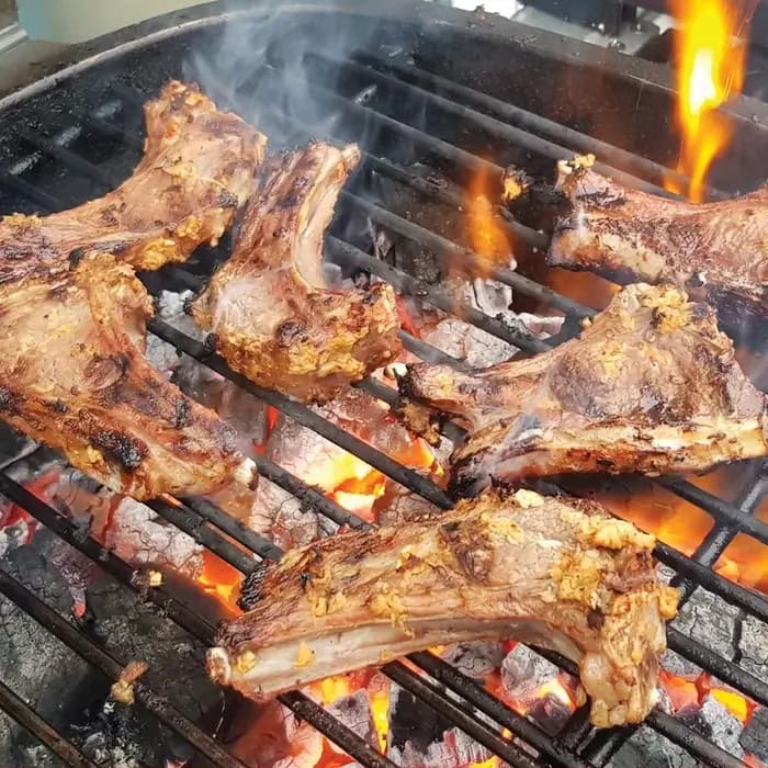 Grilled meat pieces on a charcoal grill with visible flames and smoke, representing the nyama choma staple of Biharamulo.