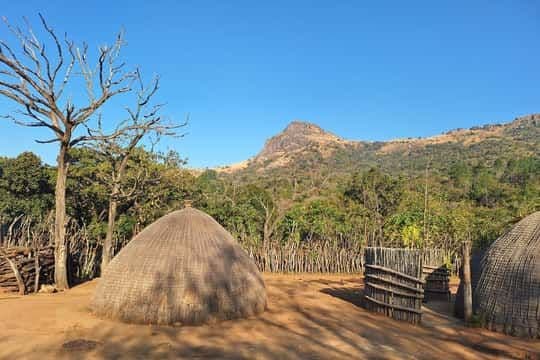 Rural village scene with thatched huts, wooden fences, and a mountain backdrop in Eswatini