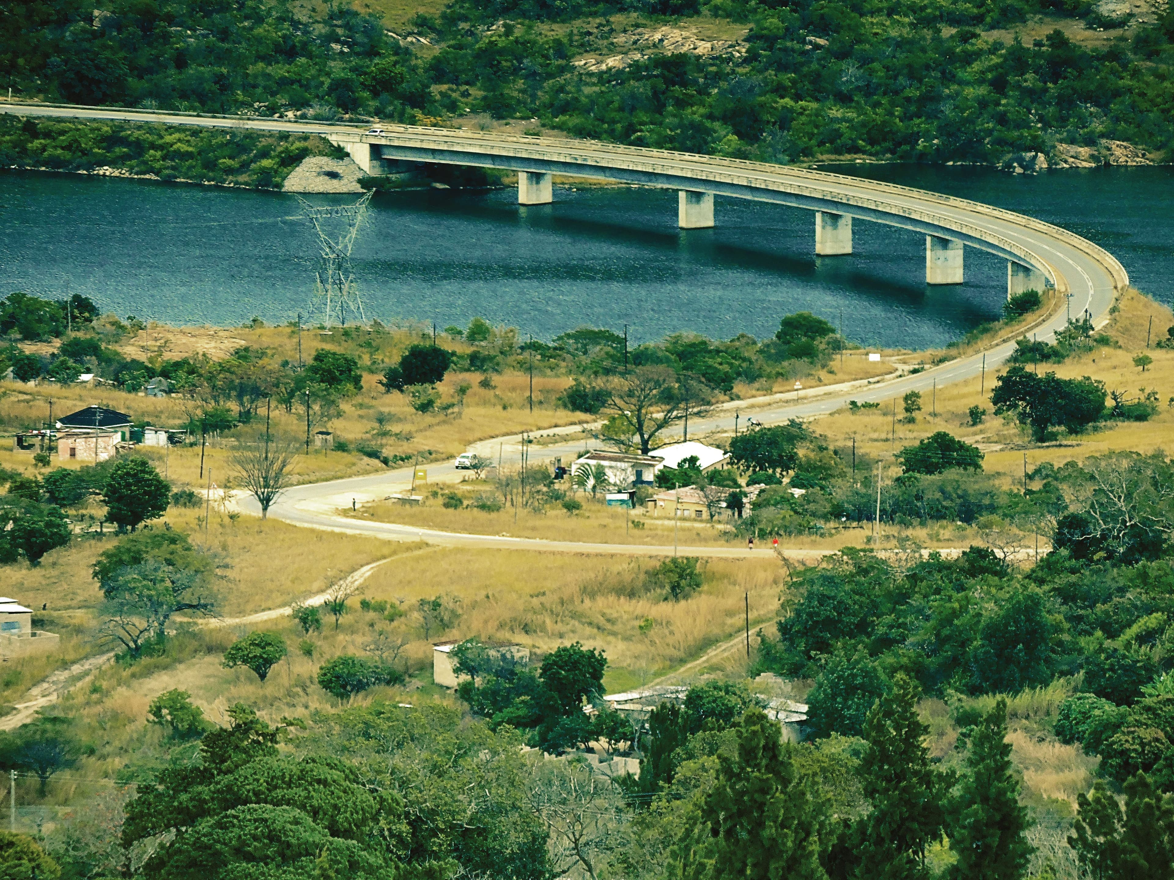 Aerial view of a curved concrete bridge spanning a river, overlooking a rural landscape with scattered houses and winding roads.
