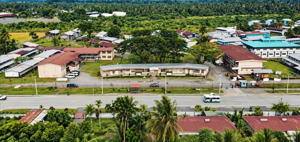 Aerial view of a tropical town with functional buildings, roads, and dense greenery