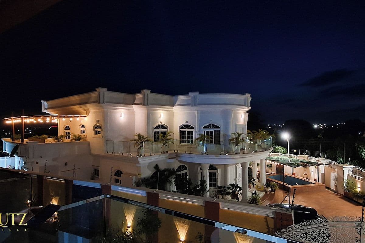 Nighttime exterior of a white multi-story hotel in Anloga with illuminated windows, balconies, and a pool area.
