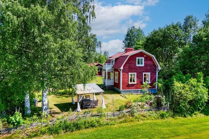 Exterior of a traditional Swedish wooden country home in Ovanåkers Kommun with surrounding forest