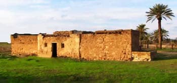 Traditional mud-brick house exterior in a grassy area in Zuwārah, Libya